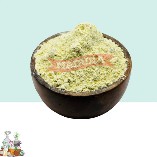 A dark brown wooden bowl filled with pale yellow-green powder, shown against a split light blue and white background. A red 'Madura' brand logo is overlaid on the powder.
