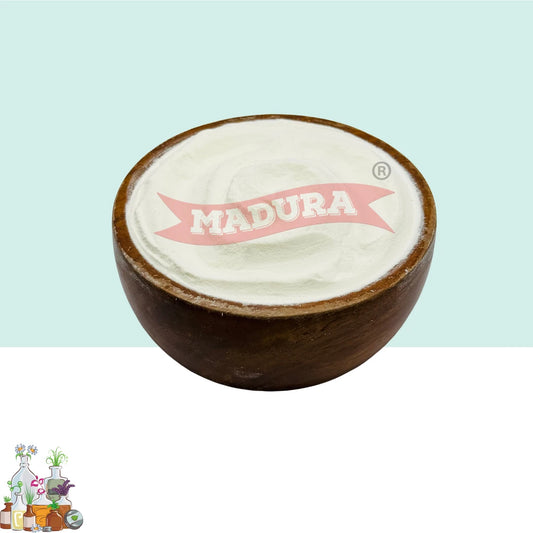 A round wooden bowl filled with white Madura soap paste, shown against a split light blue and white background with a Madura logo on top and a small decorative logo in the bottom-left corner.