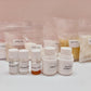 Assorted cosmetic ingredients including bottles and bags on a light pink background