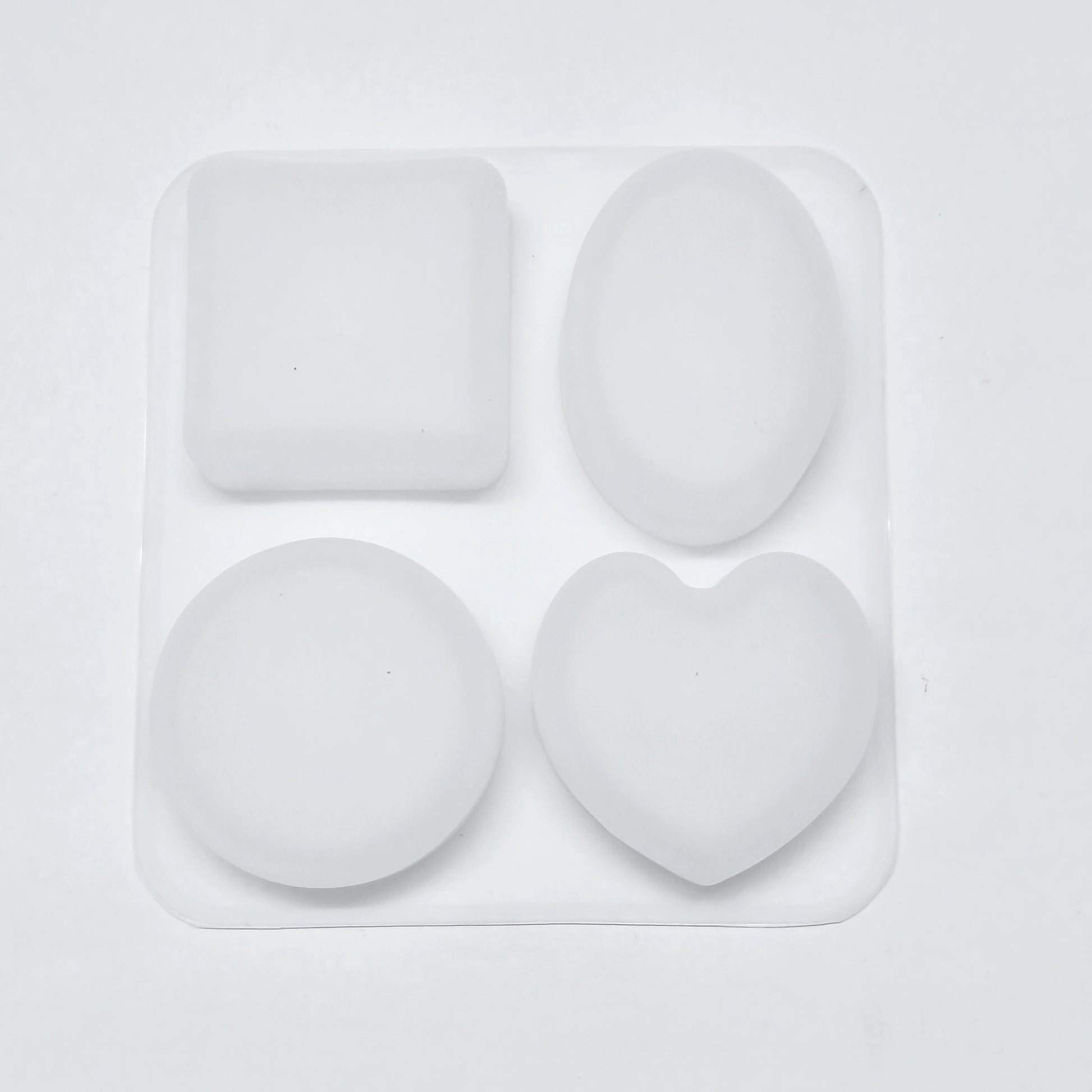 Set of four white silicone molds on a light gray background