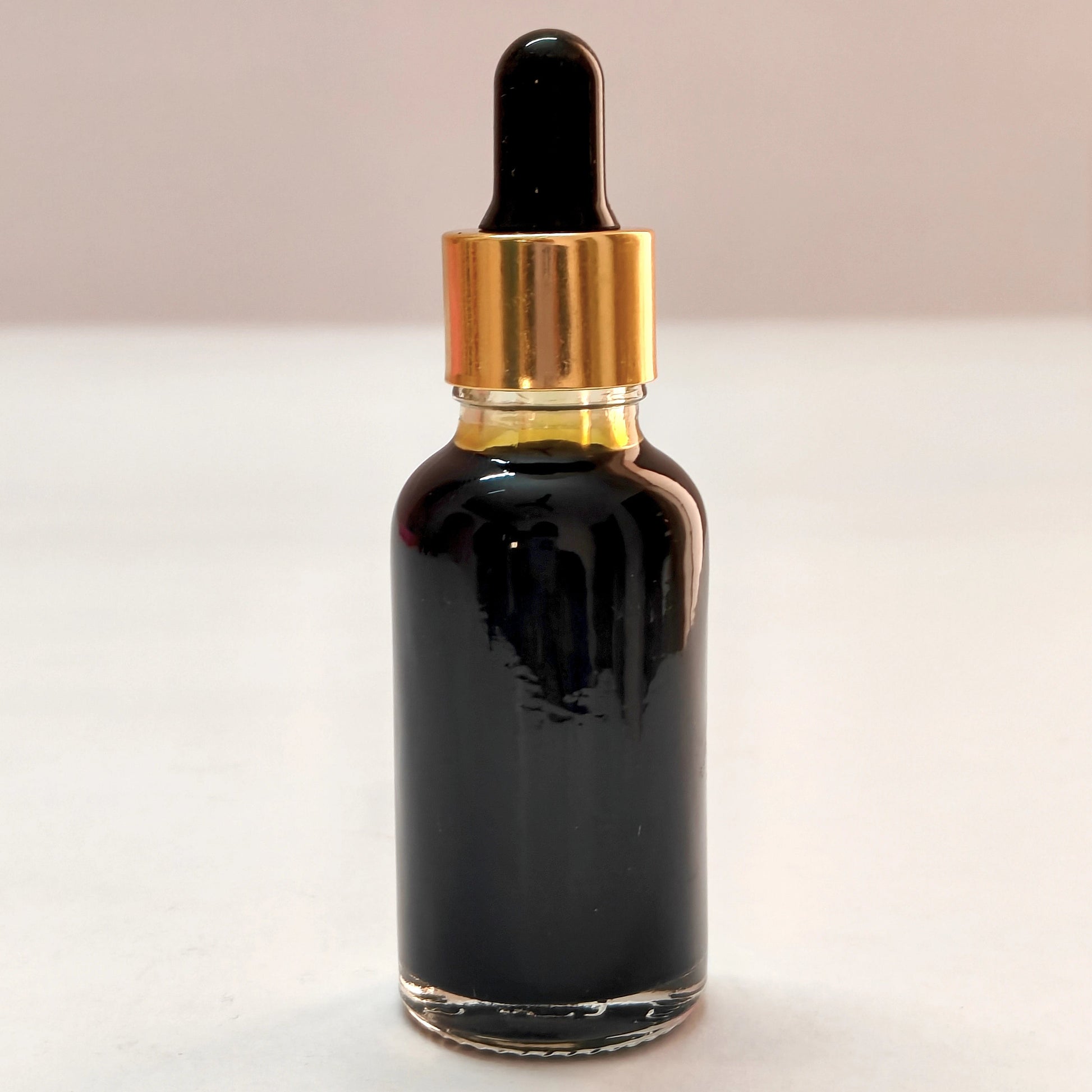 Black dropper bottle with gold cap on a white background