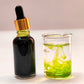 Bottle of dark liquid with dropper and glass container with green liquid on a light background