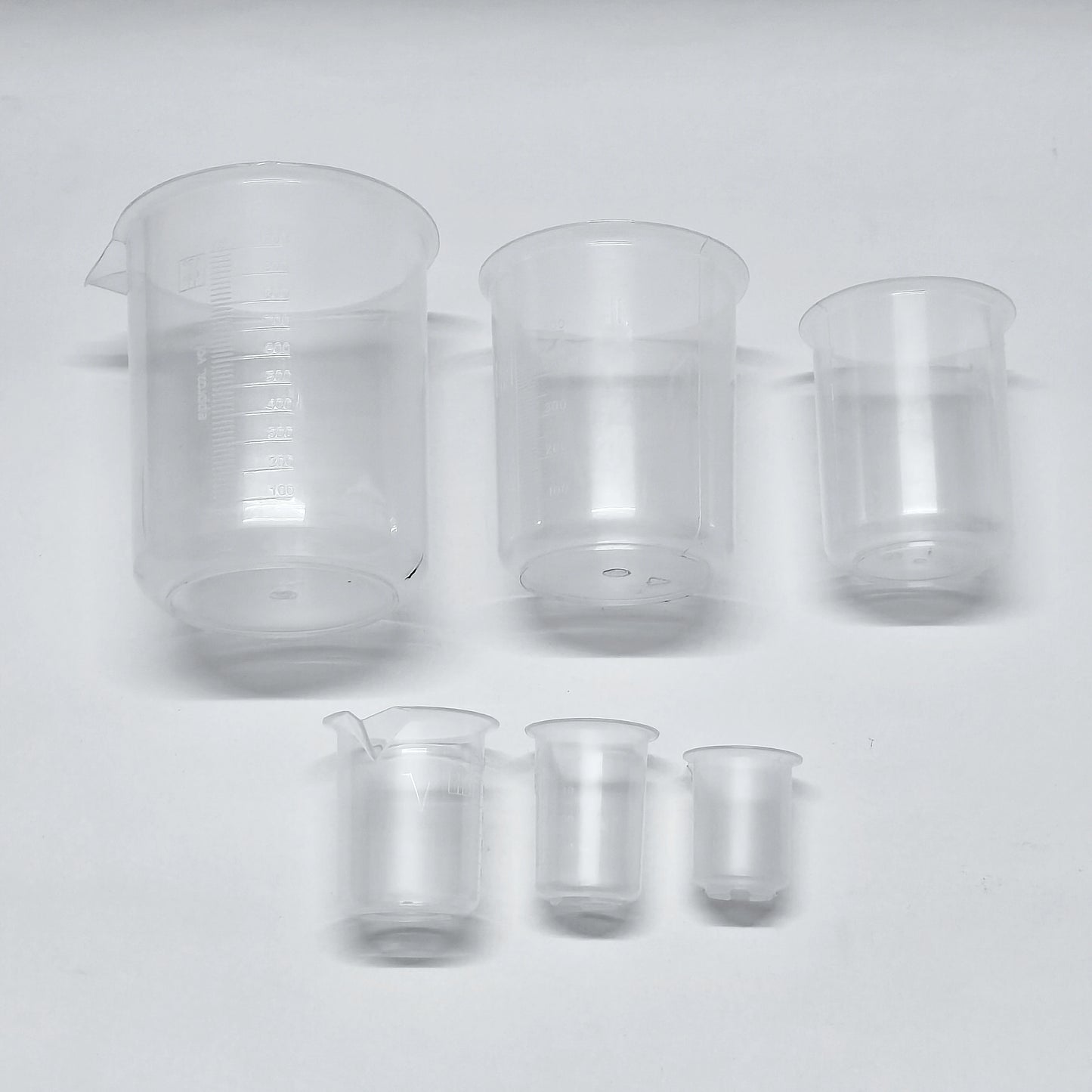 Set of clear glass beakers of different sizes on a white background