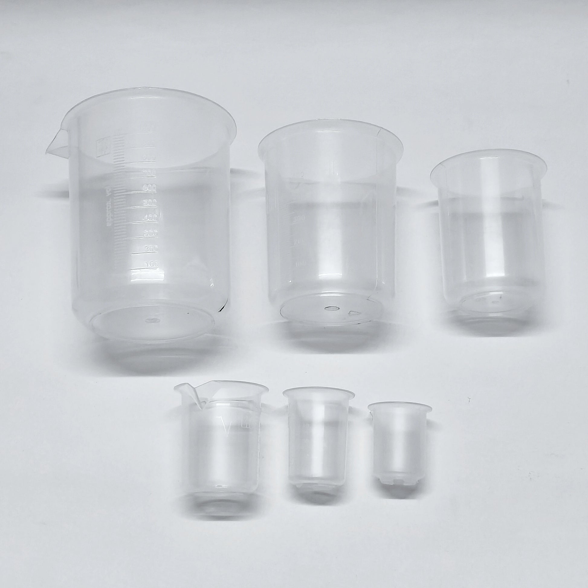 Set of clear glass beakers of different sizes on a white background