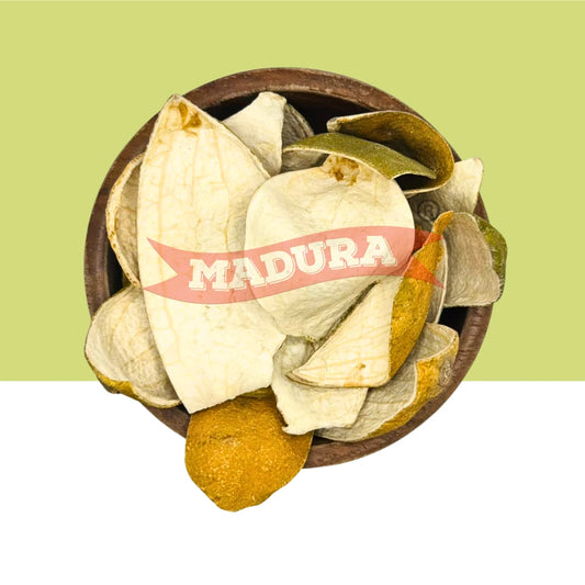 A top-down view of dried Orange Peel pieces arranged in a round brown bowl, with a red banner across the center reading 'MADURA'. The background is split horizontally with a light yellow-green upper half and white lower half.
